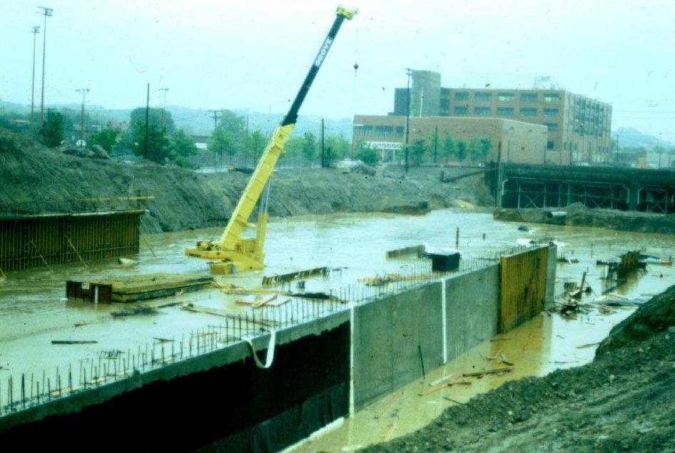 Construction of the Southwest Corridor rail lines and park in Jamaica Plain in the early 1980s. This view is looking from Everett St. towards Jamaica Plain High School. A catastrophic rain created this flood, just before the main drainage hookup was completed. Photograph courtesy of Will and Sharlene Cochrane.